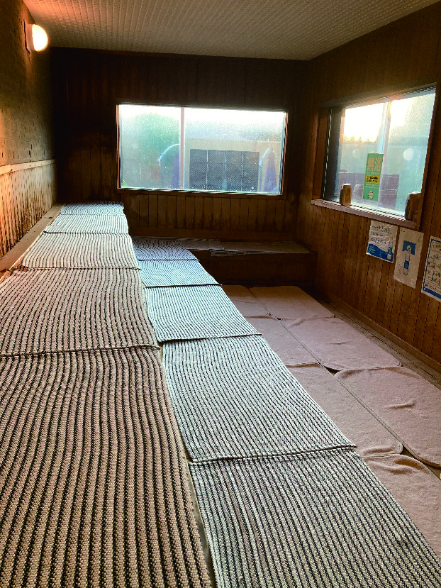 筑紫の湯の広々とした木製サウナ室と、きれいに並べられたサウナマット