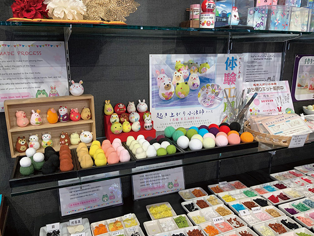 人気観光地・湯布院のおみやげ店「ちりめん細工館」に併設された体験工房。同店で人気の愛らしい起き上がり小法師を、目や耳、花などのパーツを選びながら手作りする体験が楽しめる。旅の思い出やおみやげにもぴったり。